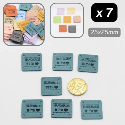 Lot de 7 étiquettes carrées « Handmade with love » en simili cuir bleu, accessoires couture ACCESSOIRES LEDUC, 25x25mm, comparées à une pièce de monnaie.